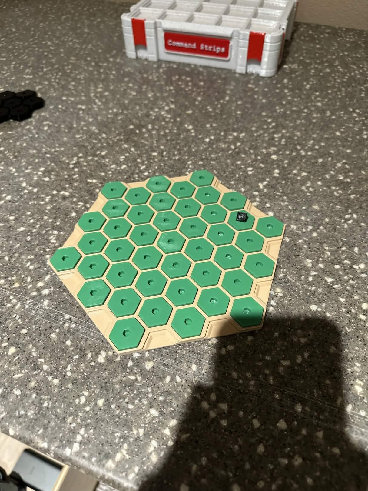 3D printed hexagonal game board with green hex tiles on a tan base